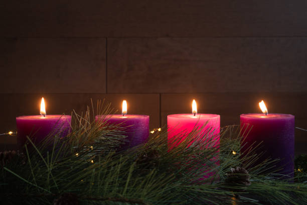 istock Four advent pillar candles burning against wood background 1355135264