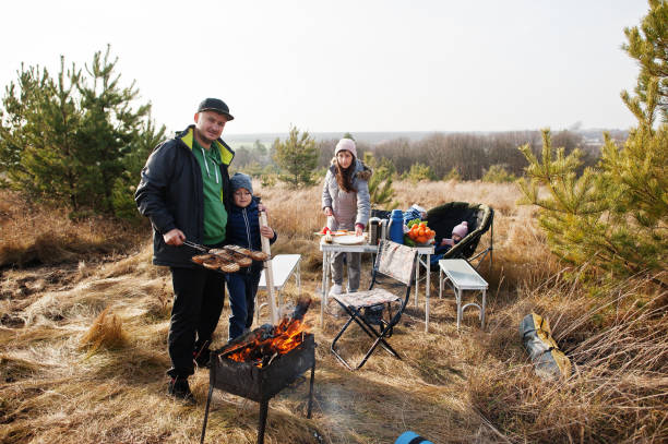 istock Family barbecuing on a deck in the pine forest. Bbq day with grill. 1355137577