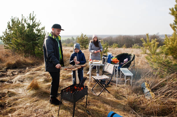 istock Family barbecuing on a deck in the pine forest. Bbq day with grill. 1355137613