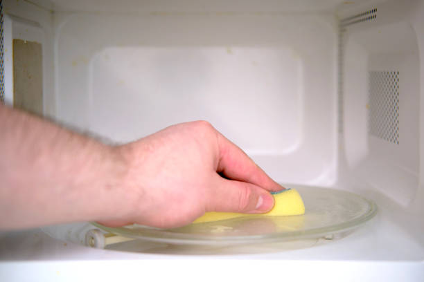 istock A man hand with a yellow sponge washes the microwave oven 1355137616