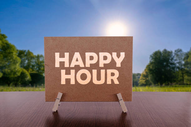 istock Happy hour text on card on the table with sunny green park background. 1355137638