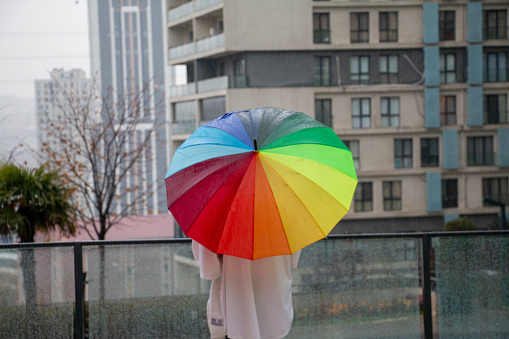 Woman hand with umbrella in the rain in green nature background