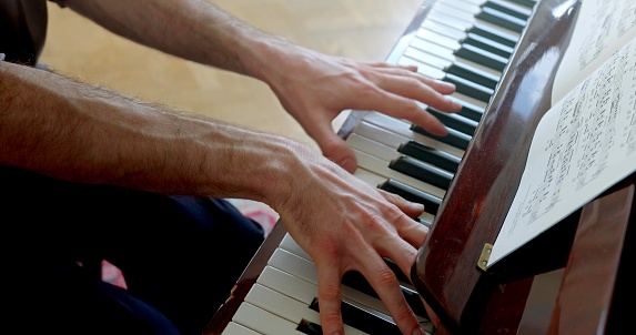 A top view of hands which are playing piano