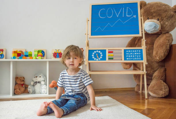 istock Cute little child using a smartphone while sitting on the floor surrounded by toys wearing face masks, during Coronavirus COVID 19 pandemic. Digital device and screen time addiction concept 1355142064