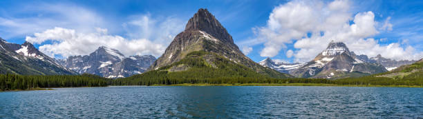 istock Spring at Swiftcurrent Lake - A panoramic view of Swiftcurrent Lake, with rugged mountain peaks towering at west shore, on a sunny Spring morning. Many Glacier, Glacier National Park. 1355142663