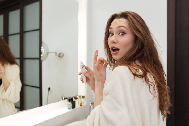 istock Surprised woman standing and applying cream in bathroom 1355143422
