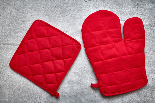 Red oven glove and potholder close up, gray background, flat lay