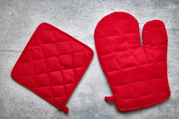 Photo of Red oven glove and potholder close up, gray background, flat lay