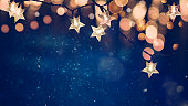 金色のボケライトを持つ青い夜の背景に星形のクリスマスストリングライト
