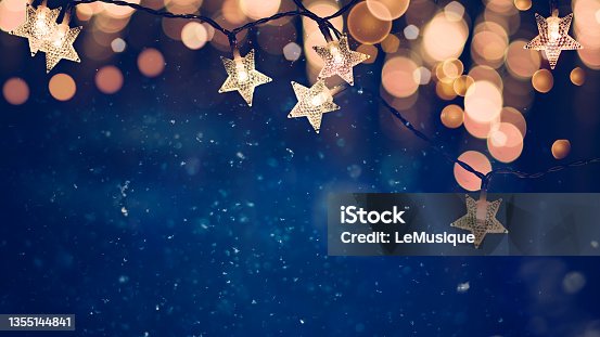 istock Star shaped Christmas string lights on blue night background with golden bokeh lights 1355144841