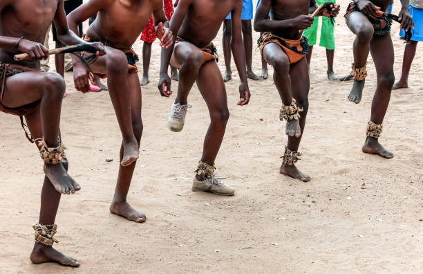 volkstanz auf dem sand. füße tanzender afrikaner auf sandiger oberfläche. - afrikanischer stamm stock-fotos und bilder