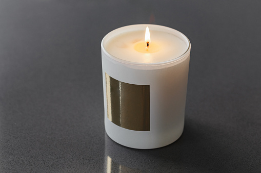 a candle in a cup in close-up with a gold-coloured label. High quality photo