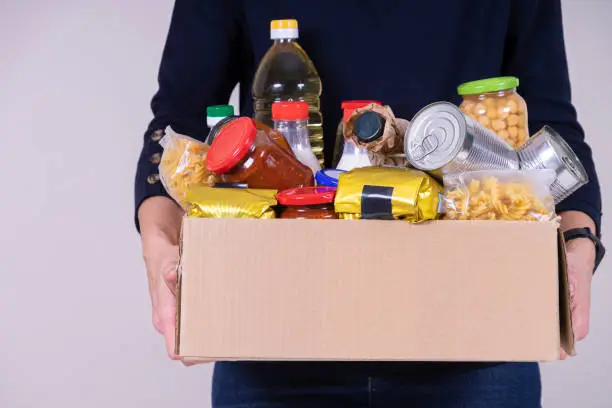 Photo of Woman volunteer hands holding food donations box with food grocery products