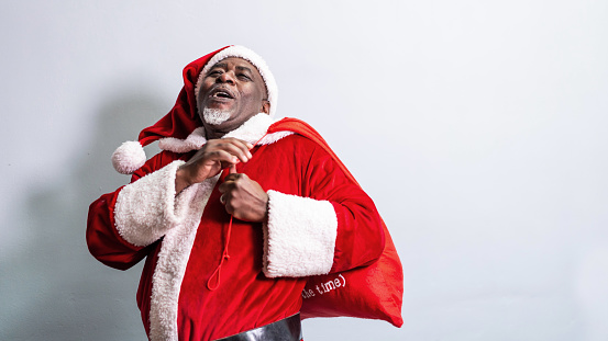 Afro Santa Claus holding a red christmas gift bag