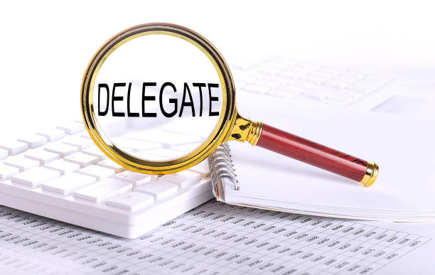 DELEGATE word through magnifying glass on keyboard on the chart stock photo