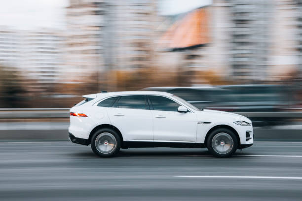 White Jaguar F-Pace car moving on the street. Ukraine, Kyiv - 23 November 2021: White Jaguar F-Pace car moving on the street. Editorial jaguar stock pictures, royalty-free photos & images