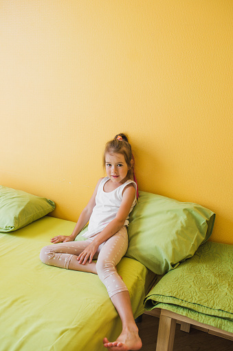 The concept of childhood. The child is sitting in bed in the yellow bedroom.