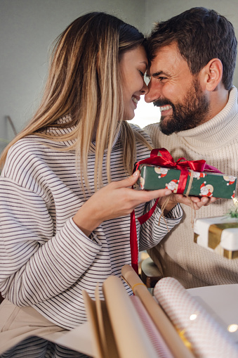 Close up shot of a young couple opening Christmas gifts