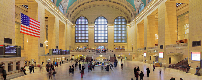 Panoramic view of the main concourse of the Grand Central Station filled with crowds of tourists and commuters.