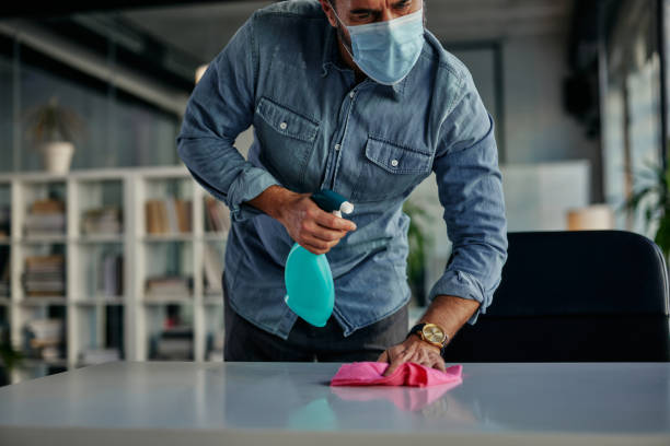 istock Sanitizing desk surface during COVID-19 pandemic 1355154431