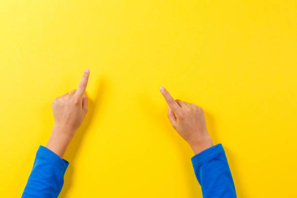 istock Kid hands pointing to something on yellow background 1355156799