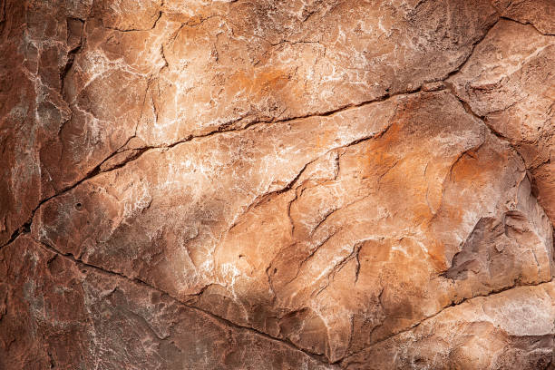 istock Textured brown rock background. Glare from the sun. 1355157552
