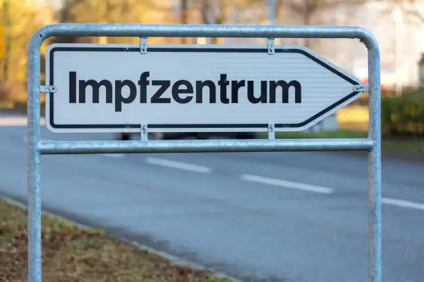 outdoor sign with the german word Impfzentrum, Street in background