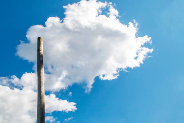 a picture of Clouds floating in a blue sky near a wooden pole