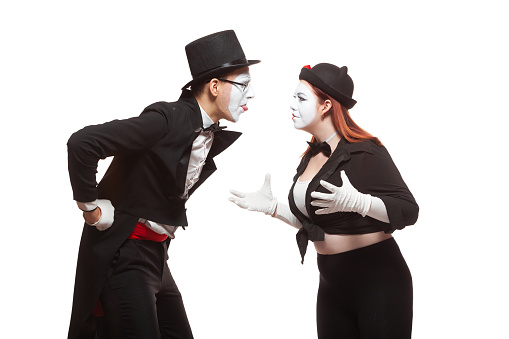 Portrait of two mime artists performing, isolated on white background. Man shows his tongue to a woman. Symbol of quarrel, family problems, domestic violence.