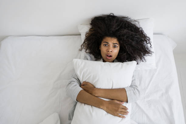 istock Scared mixed race woman lying on bed, hug pillow 1355161355