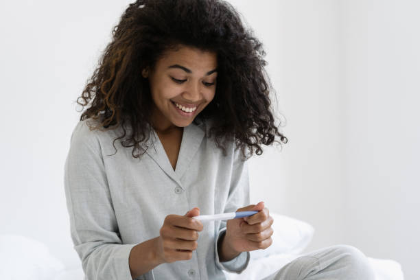 istock Happy mixed race woman look at pregnancy test 1355161478