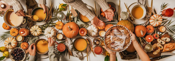 People eating over fall festive table set, top view Autumn table set for Thanksgiving day celebration or gathering dinner. Flat-lay of people eating and celebrating over table with pumpkin soup, charcuterie board, apple pie and candles, top view foxys_forest_manufacture stock pictures, royalty-free photos & images