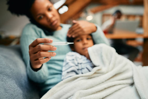 Close-up of black mother measuring sick son's temperature. Close-up of African American mother using thermometer and measuring temperature or her sick son at home. flu virus stock pictures, royalty-free photos & images