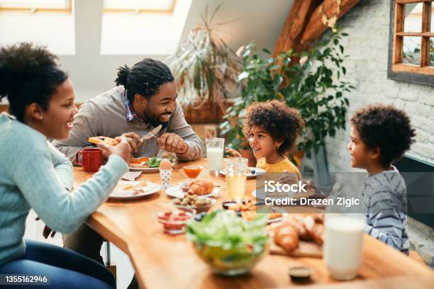 Happy African American Family Enjoying In Conversation While Eating Breakfast Together At Dining Table Stock Photo - Download Image Now