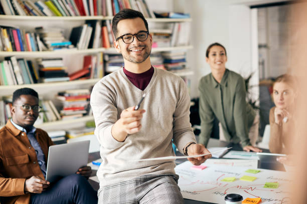 istock Happy businessman giving presentation to his creative team during a meeting in the office. 1355163473