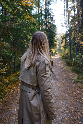 A woman traveler walks through the forest. Beautiful nature landscape in woods. Hiking journey on tourist trail. Outdoor adventure. Travel and exploration. Healthy lifestyle, leisure activities