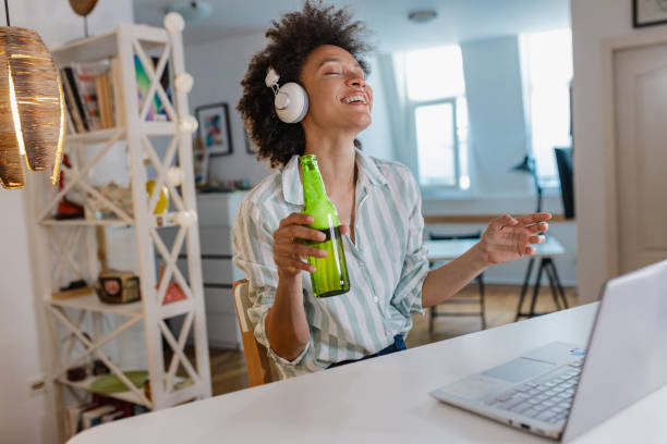 woman is attending online party and drinking beer at home - after work beautiful people beer beer bottle imagens e fotografias de stock