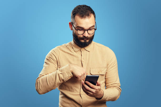 istock Serious handsome caucasian man using smartphone on blue background 1355168722