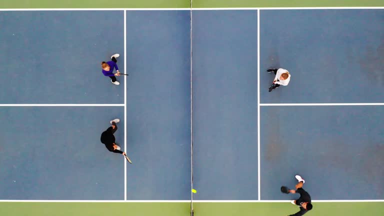 A group of young adults playing Pickleball on an outdoor court.