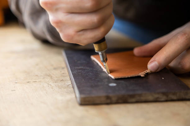 istock Craftsman machines edge of natural stuff workpiece use professional curly knife. Leather workshop 1355169542