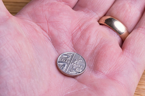 Five pence piece on the palm of a hand.