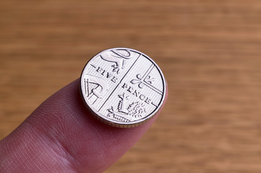 Five pence piece on someone's index finger.