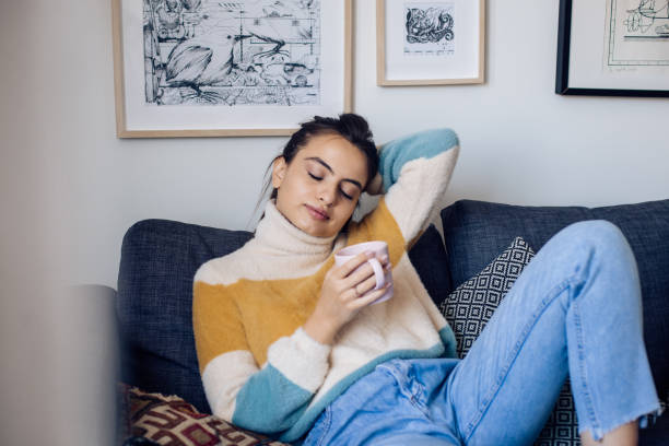 istock Beautiful girl drinking coffee and contemplating on the sofa 1355174128