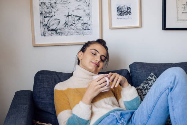 istock Beautiful girl drinking coffee and enjoying on the sofa 1355174131