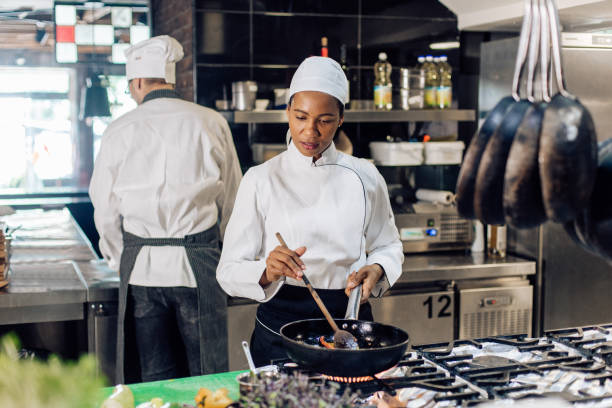 istock African-American cooker working at the restaurant kitchen, together with her chef 1355176002