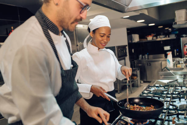 istock Young woman learning from the chef how to cook at the restaurant kitchen 1355176008