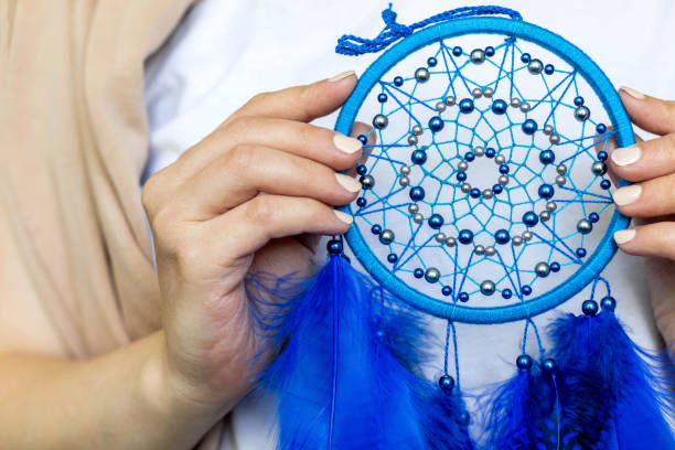 istock Closeup artistic woman posing holding dreamcatcher with bright blue feathers artwork 1355179045