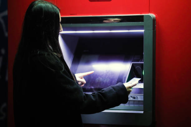 istock Young Woman Using ATM Withdrawing Money With QR Code 1355179133