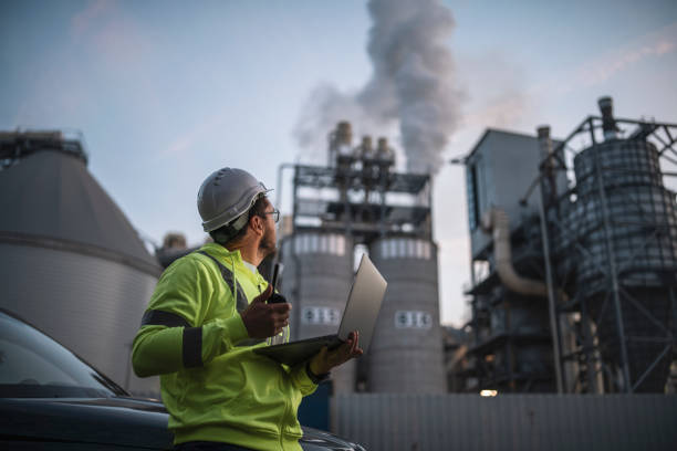 ingenieur, der mit laptop arbeitet und ein problem auf walkie talkie während kraftwerksproblemen meldet. - petrochemical plant stock-fotos und bilder