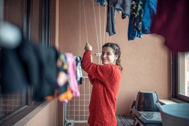 istock Young Smiling Woman Hanging Up Clothes 1355188674
